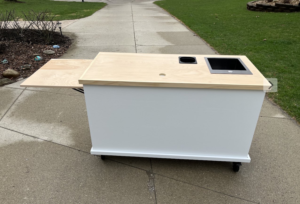 White coffee cart with a custom natural wood top, a drop-in sink and a large matching wood-top shelf