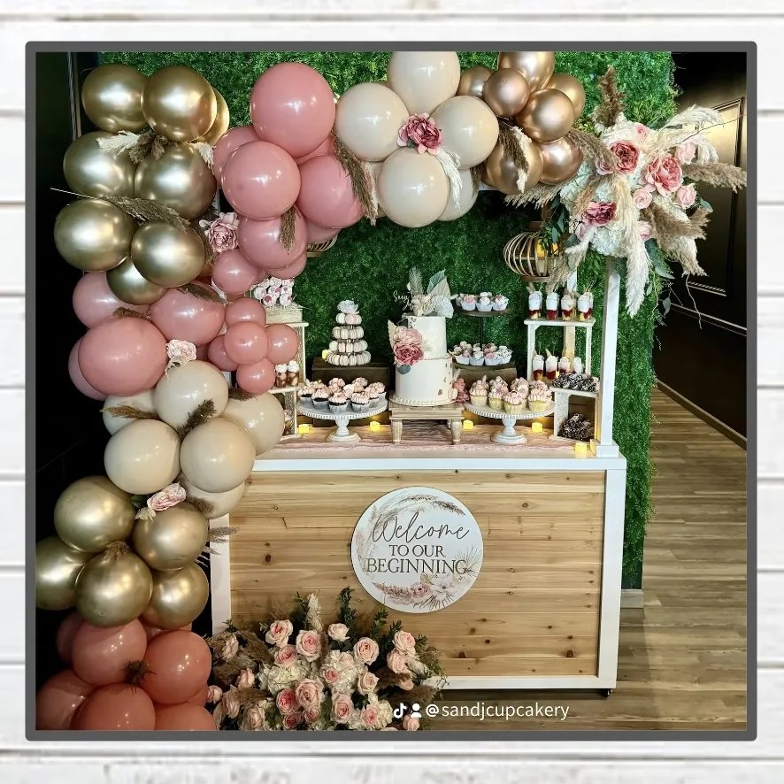 S&J Cupcakery dessert display on a custom cedar cart with a balloon arch, cake, macarons and cupcakes